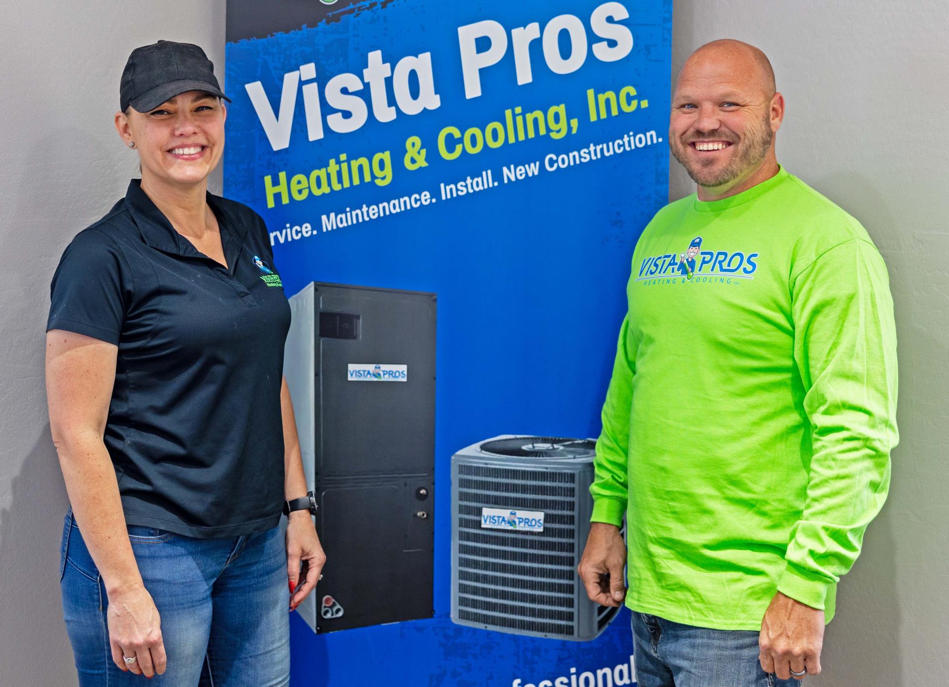 A woman and man stand in front of a Vista Pros banner