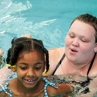 Young girl taking swimming lessons from instructor