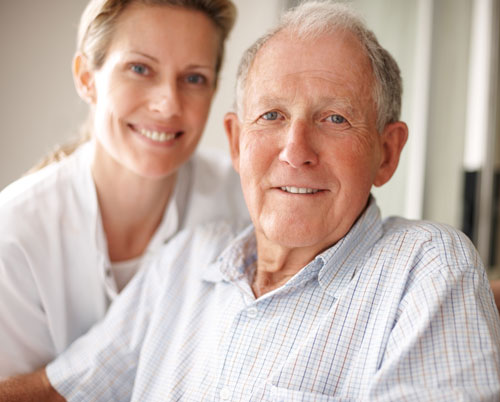 Elderly man with young woman (nurse) in background.